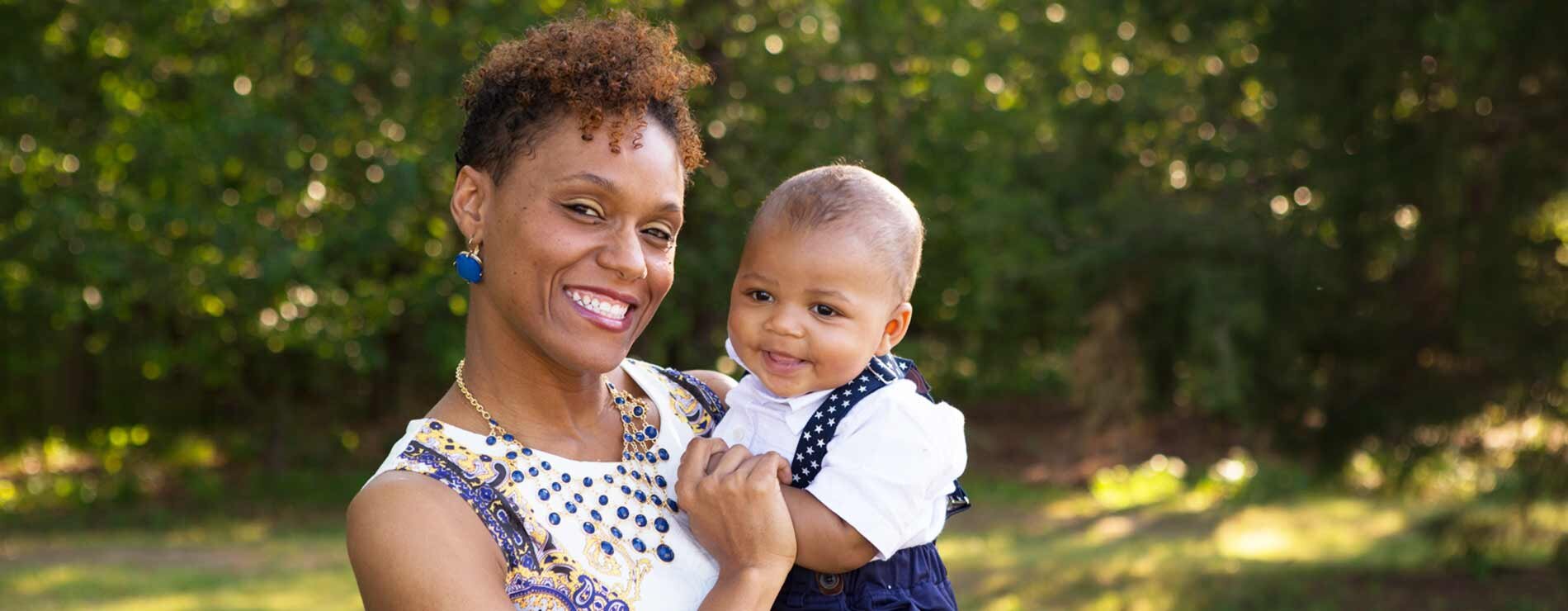 A woman holding a baby and smiling.